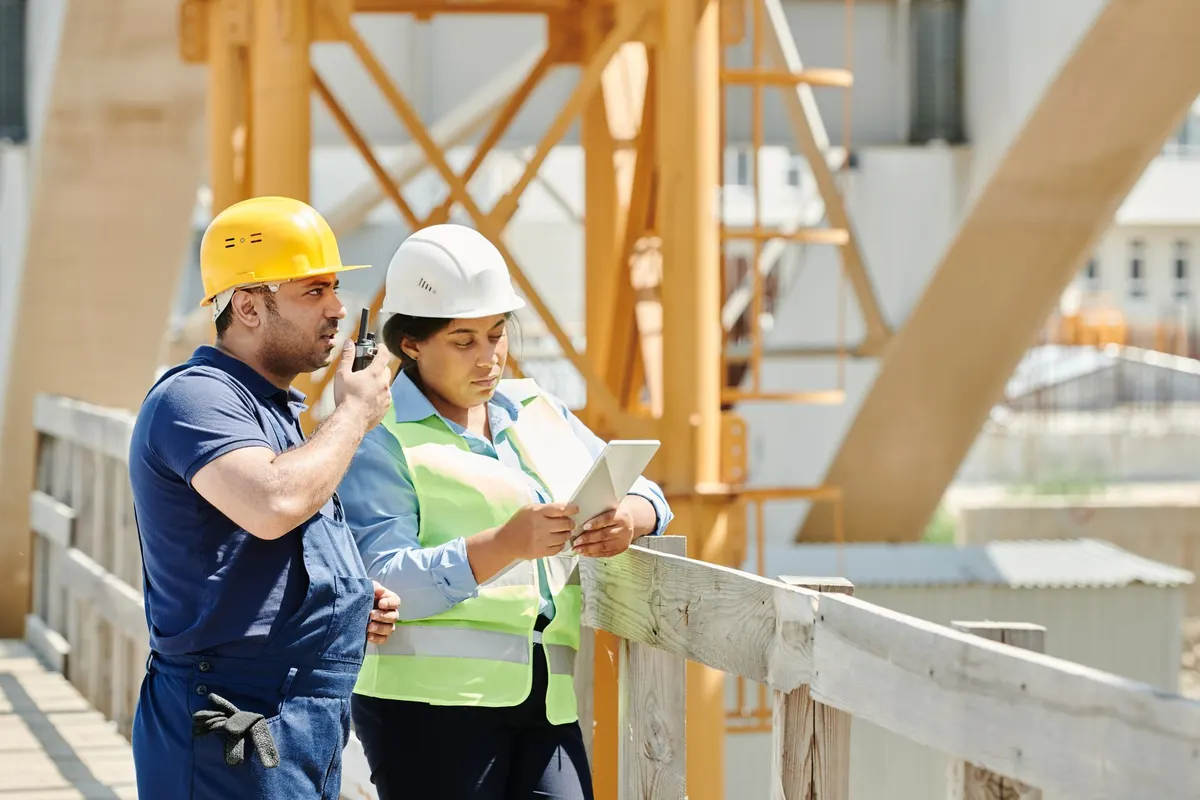 Construction workers using a tablet and radio on a job site
