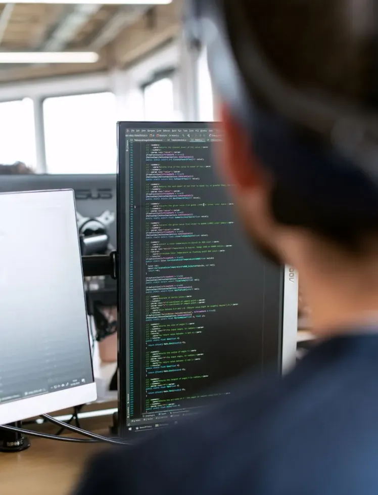 Engineer reviewing code across dual monitors