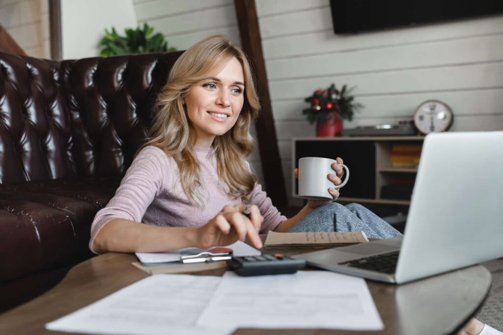 Happy Caucasian woman managing household budget, calculating bills, paying online for services taxes