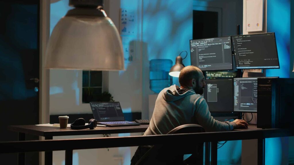 IT system engineer coding interface on multiple monitors