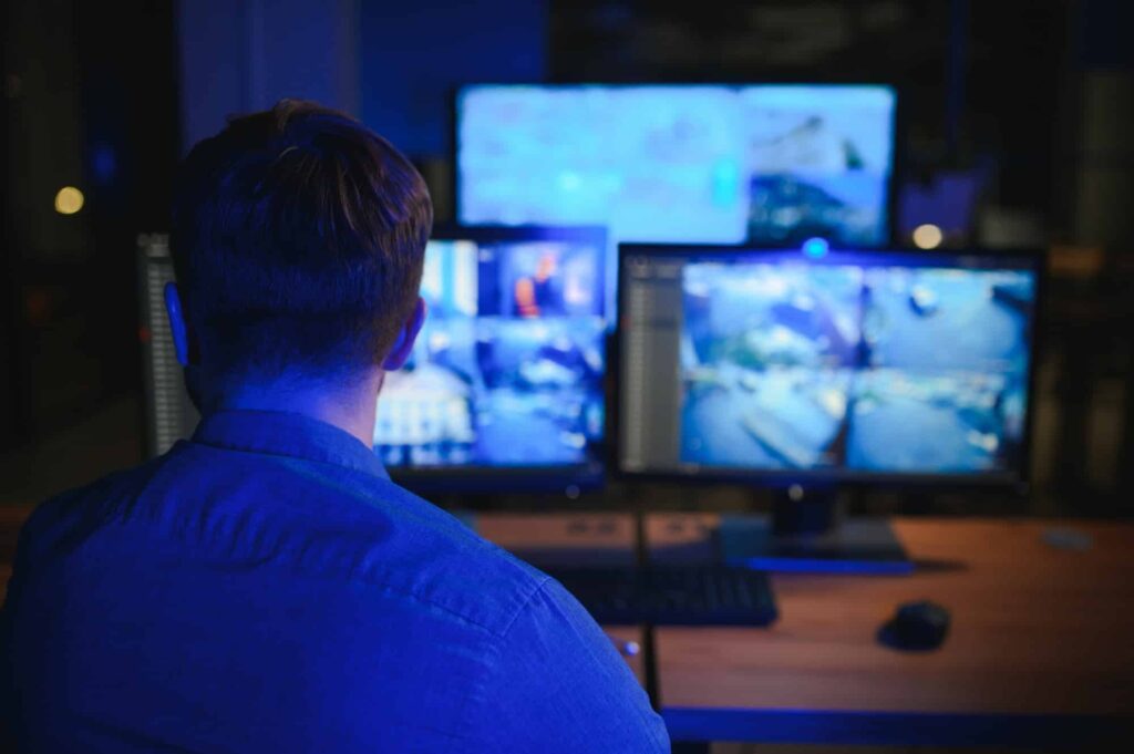 Security operator controls CCTV cameras in office at night. Modern security system