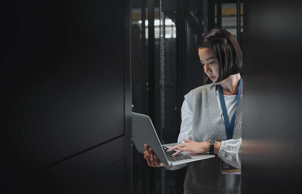Woman with laptop, datacenter and information technology, engineer and server room with software up